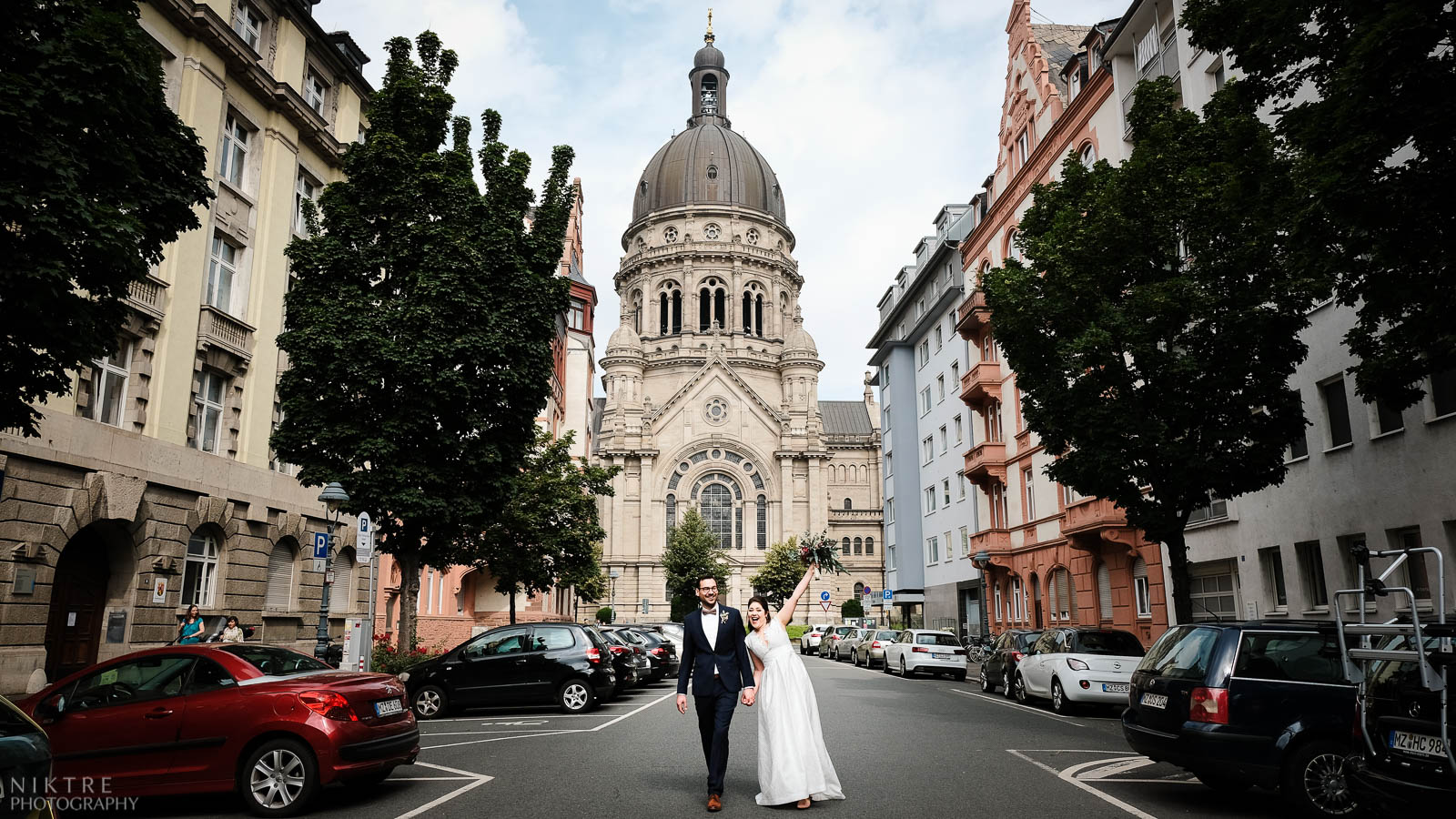 Brautpaar wird vom Hochzeitsfotograf Mainz abgelichtet mit Christuskirche im Hintergrund