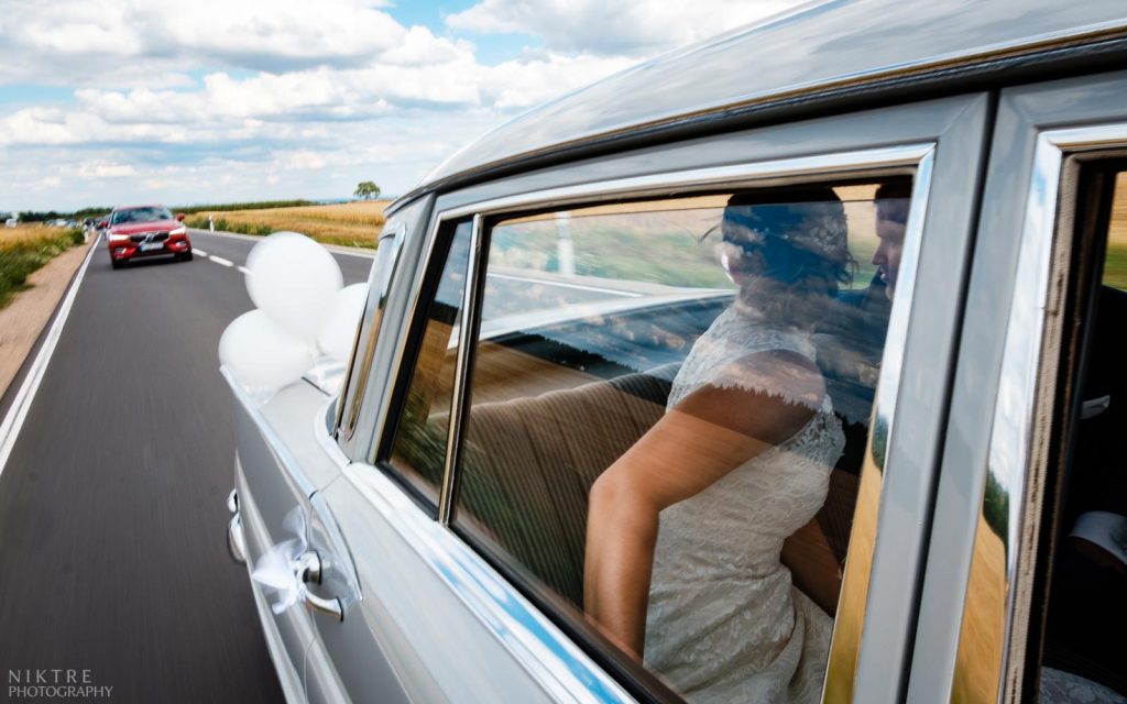 Hochzeitsfotograf Frankfurt macht Foto von Braut und Bräutigam, die sich das Hochzeitskorso anschauen