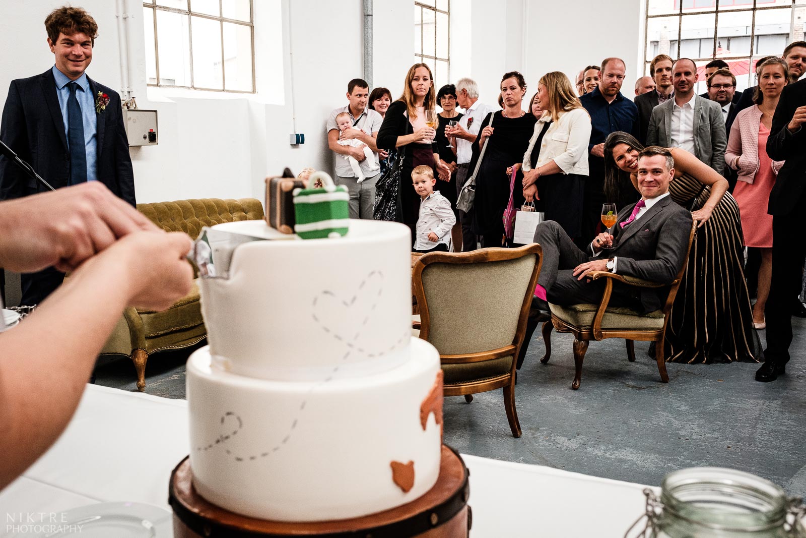 Hochzeitsfotograf Wiesbaden fotografiert das Anschneiden der Hochzeitstorte und die Gaeste schauen gebannt zu